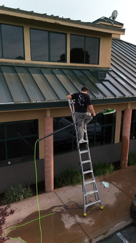 Supreme Clean technician using a water-fed pole to clean commercial building windows in El Dorado Hills